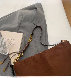 Detail of faux suede shoulder bag featuring a vintage gold ring and braided strap accents