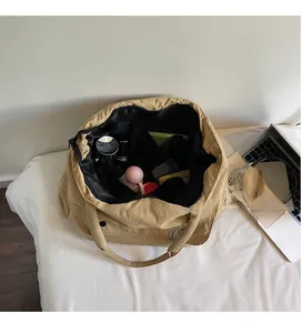 Geräumige khakifarbene Nylon-Tote-Bag mit Innenfächern und verstauten Alltagsgegenständen