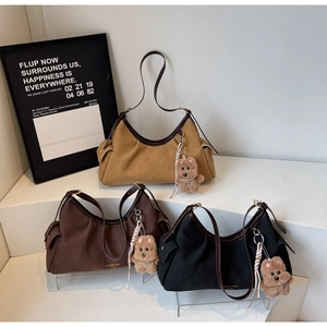 Dettaglio di borse tote in tela color cammello, marrone e nero con ciondoli a orsetto