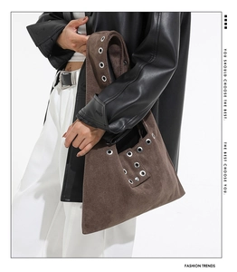Detail of brown suede tote bag with large silver eyelets and street style design
