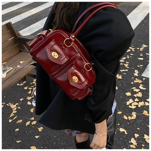 Macro detail of wine red polished leather shoulder bag with vintage gold turn-lock pockets
