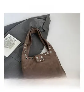Détail du sac hobo en daim marron avec œillets métalliques argentés et rabat supérieur
