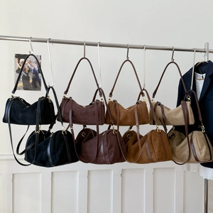 Détails des sacs Boston en daim en quatre couleurs suspendus sur un présentoir mural
