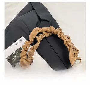 Detail of the light khaki scrunchie style leather strap on a fuzzy plush tote bag
