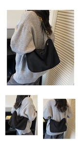 Dettaglio della borsa hobo in pelle scamosciata nera con catena dorata sulla spalla