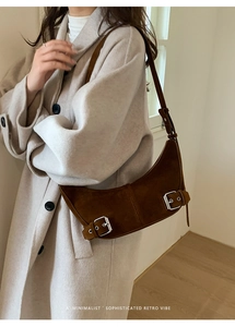 Detail view of a retro dark brown suede crescent bag with silver buckles and minimalist style