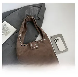 Vue détaillée des œillets argentés sur le sac hobo en daim marron avec rivets