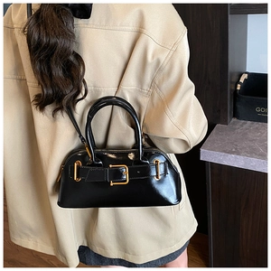 Close-up of retro black patent leather handbag with gold buckle on a stylish model