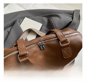 Macro shot of brown leather tote bag showing silver zippers and ethnic woven shoulder strap