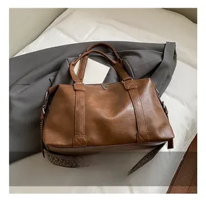 Detail of vintage brown leather bag with braided strap on grey trench coat background