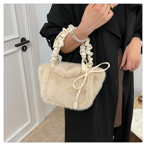 Detailed shot of cream faux fur tote bag with ruched handle and bow accessory
