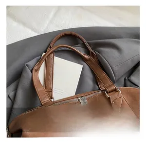 Close-up of a brown leather handbag handle with reinforced stitching and metal zippers
