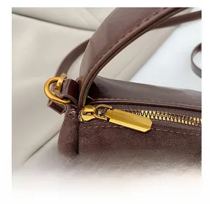 Detailed close-up of premium metal zipper and hardware on a vintage brown leather bag