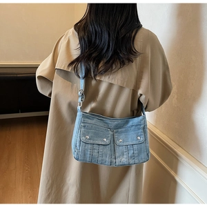 Détail du sac à bandoulière en jean délavé bleu clair avec deux poches sur un mannequin