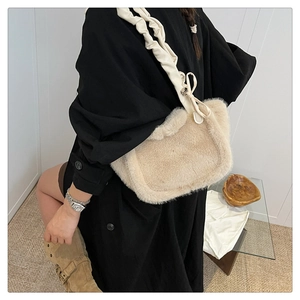 Detail view of plush beige shoulder bag with faux fur texture and bow decoration