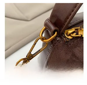 Detail of vintage gold-tone metal hook and textured leather stitching on handbag