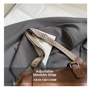 Detail view of the adjustable woven shoulder strap on a brown large capacity handbag