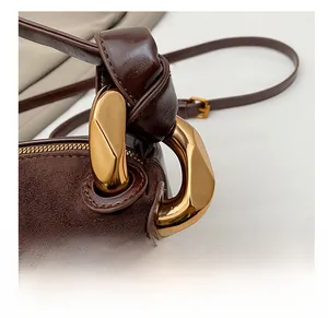 Detail of premium golden buckle and matte suede texture on dark brown handbag