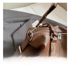 Macro view of bright silver metal hooks and smooth zippers on a brown leather tote bag
