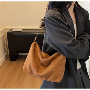 Brown suede hobo shoulder bag shown on model highlighting soft texture and drape