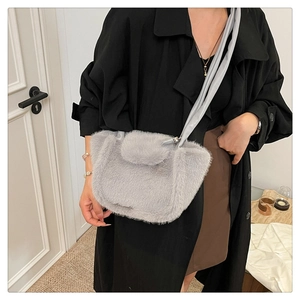 Detail of grey plush faux fur crossbody bag with thin strap shown on shoulder