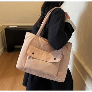 Detail of peach pink canvas tote bag featuring large front flap pocket with black snap buttons