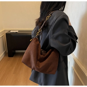 Dettaglio borsa hobo in camoscio marrone con tracolla intrecciata e fibbie in metallo oro