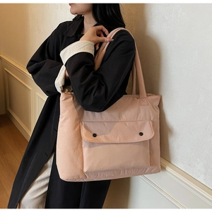 Detail of pink nylon tote bag with front pocket and snap buttons worn on shoulder