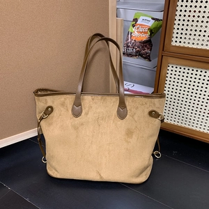 Detail of khaki suede tote bag with brown leather straps and side metal buckles
