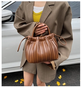 Detail of the brown pleated bucket bag with rich leather texture and stylish drawstrings