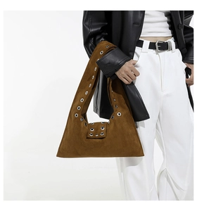 Gros plan du sac hobo en daim marron avec œillets métalliques argentés et large bandoulière