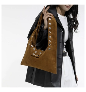 Detail of brown vintage wax leather bag with silver metal eyelets and rivet accents