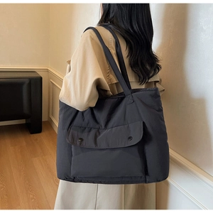 Side view of large black nylon tote bag showing flap pocket and spacious design