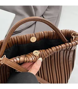 Detailed view of caramel brown pleated bucket bag with a metal magnetic closure