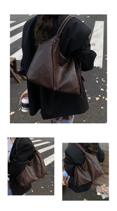 Détail du grand sac cabas marron foncé avec pompons latéraux et bandoulière tressée