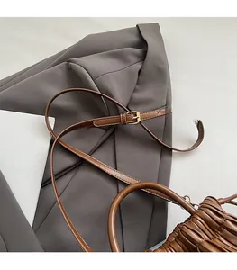 Detailed view of brown pleated leather handbag with adjustable strap and textured finish