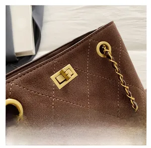 Close-up of quilted suede bucket bag featuring a gold twist-lock and chain strap