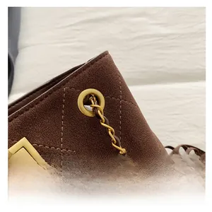 Close-up of golden metal clasp and fine diamond stitching on brown suede bucket bag