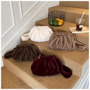 Detailed view of plush faux fur cloud bags in four colors arranged on carpeted stairs
