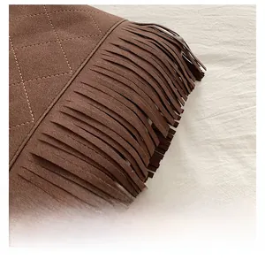 Macro detail of dark brown suede bucket bag with fringe tassels and quilted embroidery