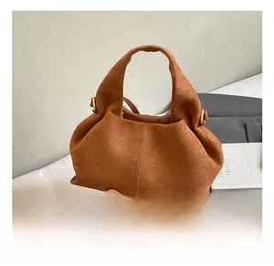 Detail of brown faux suede cloud bag showing soft pleated structure and golden hardware