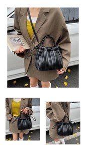 Detail of black pleated bucket bag showing textured synthetic leather and drawstring closure