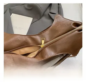 Vue macro détaillée de la fermeture éclair dorée sur un sac cabas en cuir marron