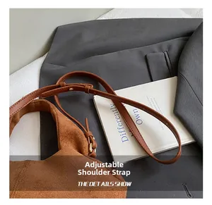 Detail showing the adjustable shoulder strap and brown suede texture of the handbag
