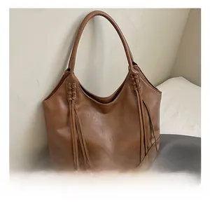 Détail du sac hobo en similicuir marron avec accents tressés et longues franges pendantes