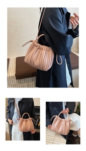 Detail view of pink pleated bucket bag showing textured clouds design and crossbody strap