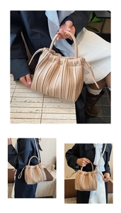 Detail view of a beige pleated bucket bag showing hand-carry and crossbody styles