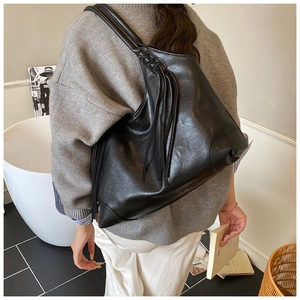 Détail d'un grand sac hobo en cuir noir avec pompon et couture triangulaire de renfort