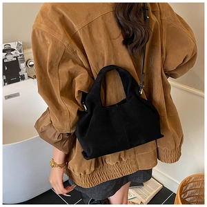 Détail du sac nuage en daim noir avec bandoulière minimaliste et texture plissée élégante