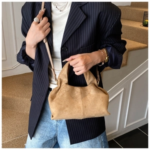 Detail of khaki suede pleated bucket bag with fine stitching and detachable shoulder strap